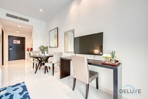 Une chambre d’hôtel moderne dotée d’un coin repas, d’un téléviseur à écran plat et d’un bureau avec une chaise.