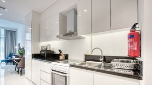 Een moderne keuken met witte kastjes, een RVS spoelbak en een rode brandblusser.