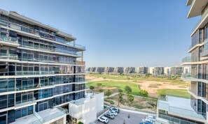 Un immeuble moderne à plusieurs étages, doté d’un parking et offrant une vue sur un terrain de golf.
