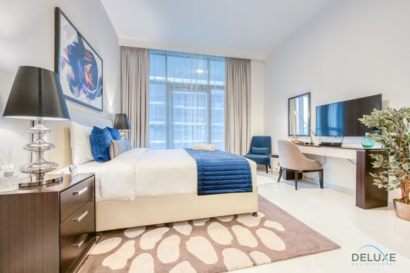 Une chambre d’hôtel moderne équipée d’un lit, d’un bureau, d’une chaise et d’une grande fenêtre.
