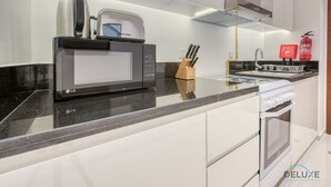 A modern kitchen with a microwave, stove, and knife block.
