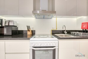 A modern kitchen with a built-in oven, microwave, and stove. There is a knife block, a sink, and a fire blanket sign.
