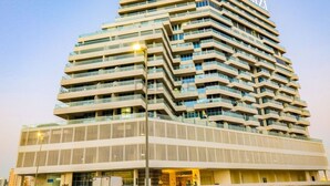 A multi-story hotel with a modern design, featuring a prominent 'AZZAI' sign on the top. - Huge Balcony Overlooking Creek Harbour with Glimpses of Burj Khalifa (Dubai)