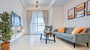 A modern living room with a grey sofa, a round coffee table, and a large window with curtains.