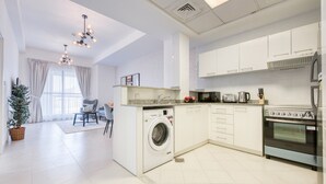 A modern kitchen with a built-in washing machine, a stove, and a dining area with a chair and table.