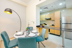 Uma zona de refeições moderna com cadeiras cor de verde-água, uma mesa redonda posta para quatro e uma luminária pendente.
