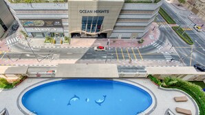 Una piscina con delfines, una carretera con coches y un edificio que dice "OCEAN HEIGHTS".