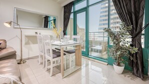Un comedor moderno con una mesa de vidrio, sillas blancas, una lámpara de pie y una planta en maceta.