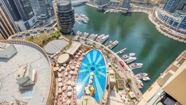 Un hotel moderno con piscina en la azotea, puerto deportivo y vistas a la ciudad.