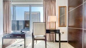 Habitación de hotel con escritorio, silla y un amplio ventanal con vistas a la ciudad.
