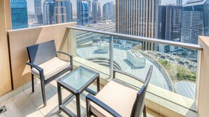 Un balcón con mobiliario de mimbre, una mesa de vidrio y vistas a la ciudad.