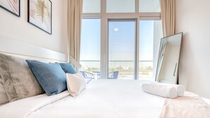 Ein Hotelzimmer mit einem großen Bett, einem Balkon mit Aussicht und einem großen Spiegel.