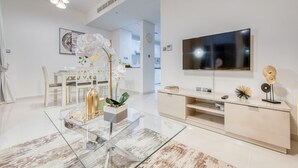 Ein modernes Wohnzimmer mit einem Glastisch, einem an der Wand montierten Fernseher und einem minimalistischen Design.