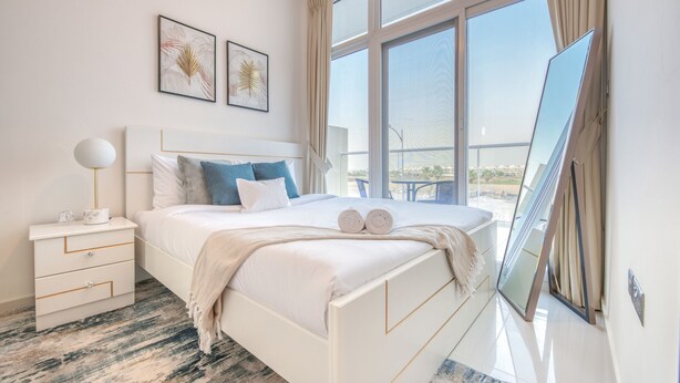 Ein modernes Schlafzimmer mit einem großen Bett, einem Nachttisch, einer Nachttischlampe und einem großen Fenster mit Blick.