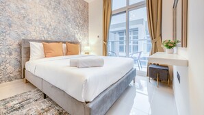 A modern hotel room with a large bed, a desk, and a view of the city.