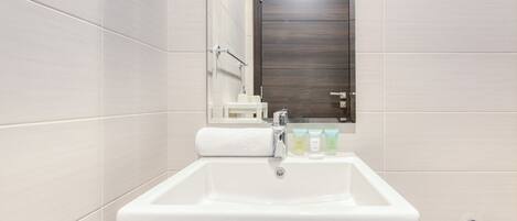 A bathroom with a white sink, a mirror, and a dark wooden door.