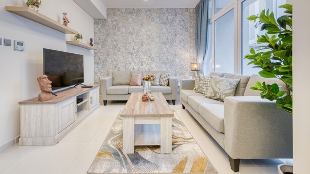 A modern living room with a flat-screen TV, a wooden coffee table, two sofas, and a large window with curtains.