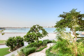 Eine Uferpromenade mit freiem Blick auf das Meer, einem gepflasterten Gehweg und üppiger Vegetation.