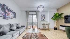 A modern living room with a sofa, a coffee table, a chandelier, and artwork on the walls. - Elegant 2BR at Bahar 2 JBR by Deluxe Holiday Homes (Dubai)