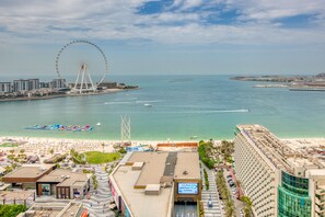 A coastal cityscape with a prominent Ferris wheel, beachfront hotels, and a clear view of the sea.