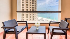 A balcony with two chairs and a small table, overlooking a beach and a Ferris wheel. - Elegant 2BR at Bahar 2 JBR by Deluxe Holiday Homes (Dubai)