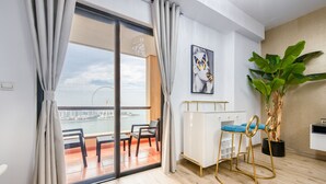 A modern living room with a large sliding glass door leading to a balcony with a view of a cityscape and a Ferris wheel. - Elegant 2BR at Bahar 2 JBR by Deluxe Holiday Homes (Dubai)