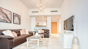 A modern living room with a brown leather sofa, a white coffee table, and a large flat-screen TV. - Fresh 2BR at Mudon Views 4 Dubailand by Deluxe Holiday Homes (Dubai)
