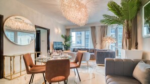 Un salon moderne avec une table à manger ronde, des sièges confortables, un grand miroir et un lustre décoratif.
