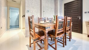 Un coin repas avec une table et des chaises en bois, une porte sombre et un mur de couleur claire.