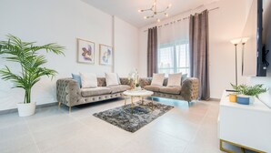 A modern living room with a sofa set, a coffee table, and a potted plant. - Whimsical 2BR at Bella Rose Barsha South by Deluxe Holiday Homes (Dubai)
