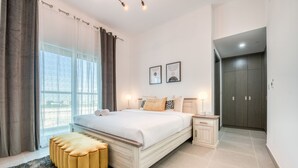 A bedroom with a large bed, bedside tables, a wardrobe, and a view of the outdoors. - Whimsical 2BR at Bella Rose Barsha South by Deluxe Holiday Homes (Dubai)