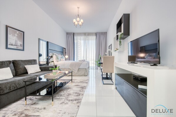 A modern living room with a sofa, coffee table, TV, and a dining area.