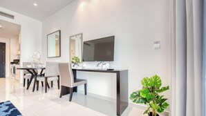 Een moderne woonkamer met een eethoek, een flatscreen televisie en een kamerplant.