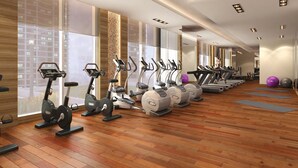 Een sportschool met meerdere loopbanden, hometrainers en fitnessballen.