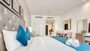 Hotelkamer met een groot bed, een bureau, een stoel en een zichtbare badkamer door een open deur.