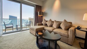 Ein modernes Hotelzimmer mit großem Fenster, einer Couch, einem Couchtisch und einer Lampe.