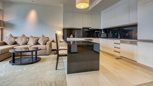 Eine moderne Küche mit weißen Schränken und einer zentralen Kochinsel, ein Essbereich mit rundem Tisch und einer Couch, sowie eine Pendelleuchte über der Insel.