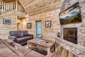 Relax by the fireplace in this inviting living room, featuring a leather sofa and wooden coffee table.