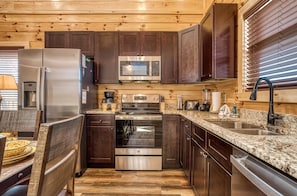 Enjoy cooking in this fully equipped kitchen with a refrigerator, microwave, and oven, as well as a dining area with a table and chairs.