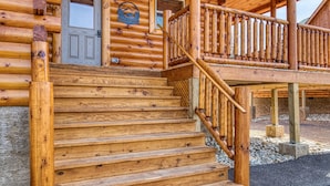 Une cabane en bois avec une porte d’entrée, une petite fenêtre et un escalier en bois menant à un balcon.