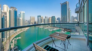 Un balcón con vistas a un puerto deportivo y al horizonte de la ciudad, con edificios altos y cielo despejado.