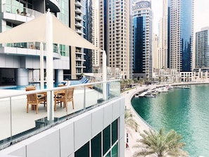 A modern hotel with a rooftop pool area, surrounded by high-rise buildings and a marina.