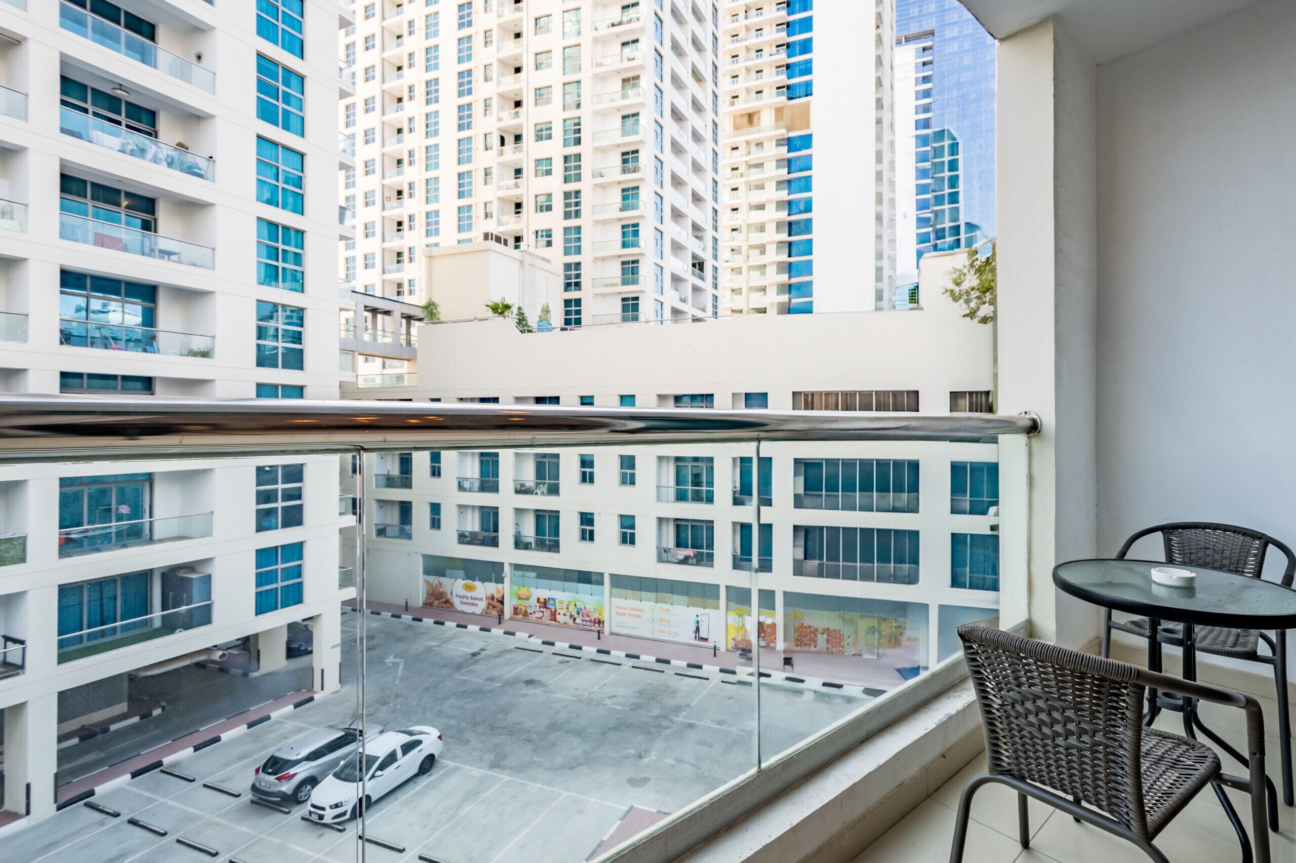 Un balcón con vistas a un estacionamiento y un edificio alto.