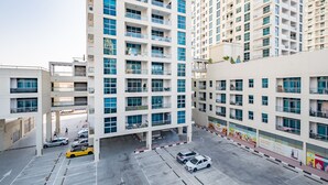 Un immeuble résidentiel à plusieurs étages, doté de balcons, d’un espace de stationnement et d’une devanture de magasin avec des publicités.