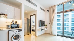 Un appartement moderne doté d’une cuisine, d’un lave-linge, d’une télévision et d’un balcon offrant une vue sur la ville.