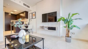 Un salón moderno con una mesa de centro de vidrio, un televisor de pantalla plana montado en la pared y una planta en maceta.
