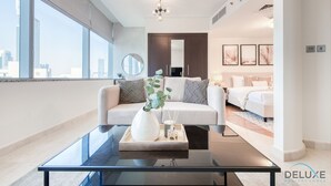 A modern hotel room with a glass coffee table, a sofa, a bed, and a city view. - Calm Studio at Sky Gardens DIFC by Deluxe Holiday Homes (Dubai)