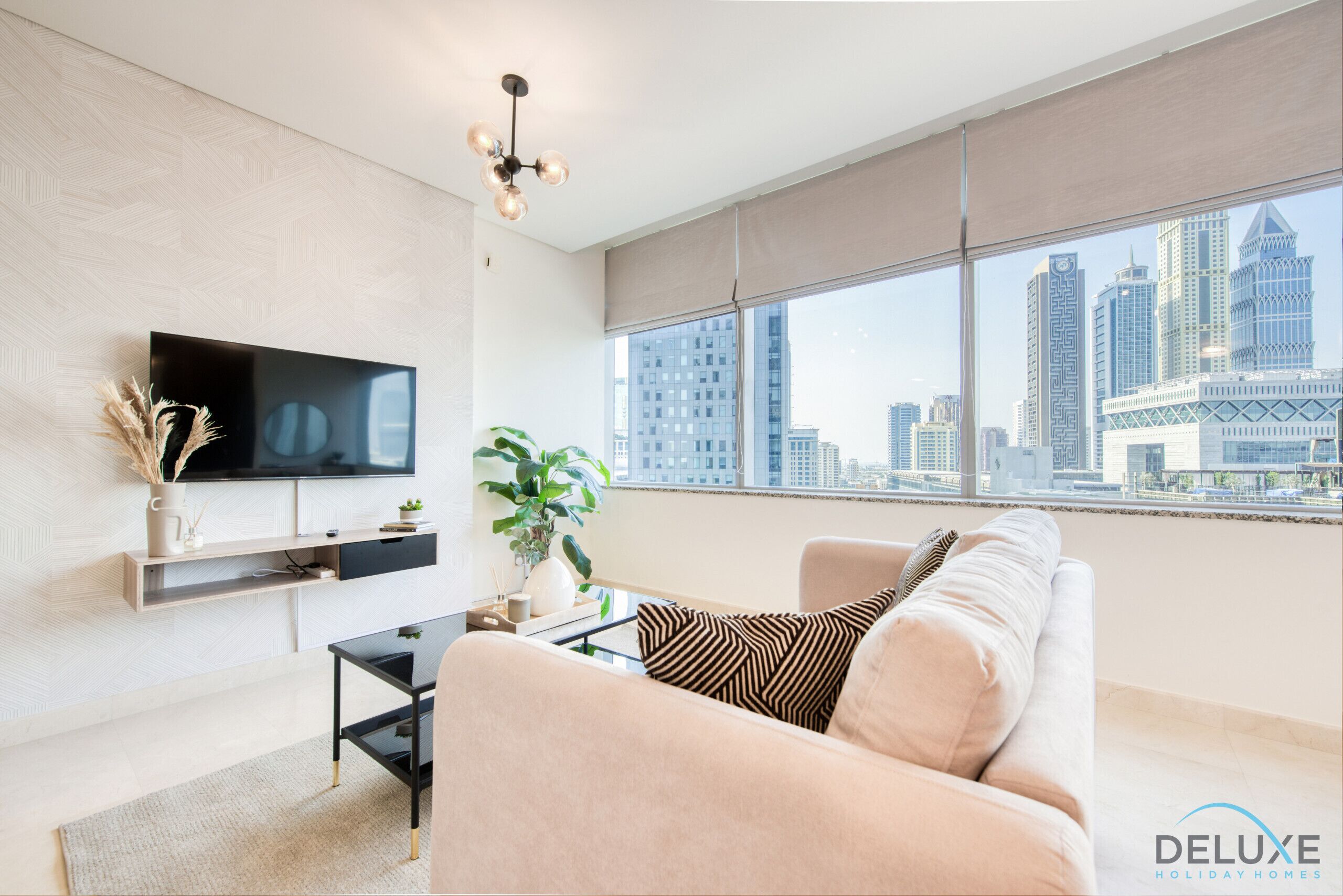 A modern living room with a large TV, a sofa, a coffee table, and a city view through large windows.