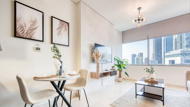 A modern living room with a dining area, large windows with a city view, and minimalist decor. - Calm Studio at Sky Gardens DIFC by Deluxe Holiday Homes (Dubai)