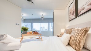 A modern hotel room with a large bed, a bedside table with a plant, and a view of the city through large windows. - Calm Studio at Sky Gardens DIFC by Deluxe Holiday Homes (Dubai)